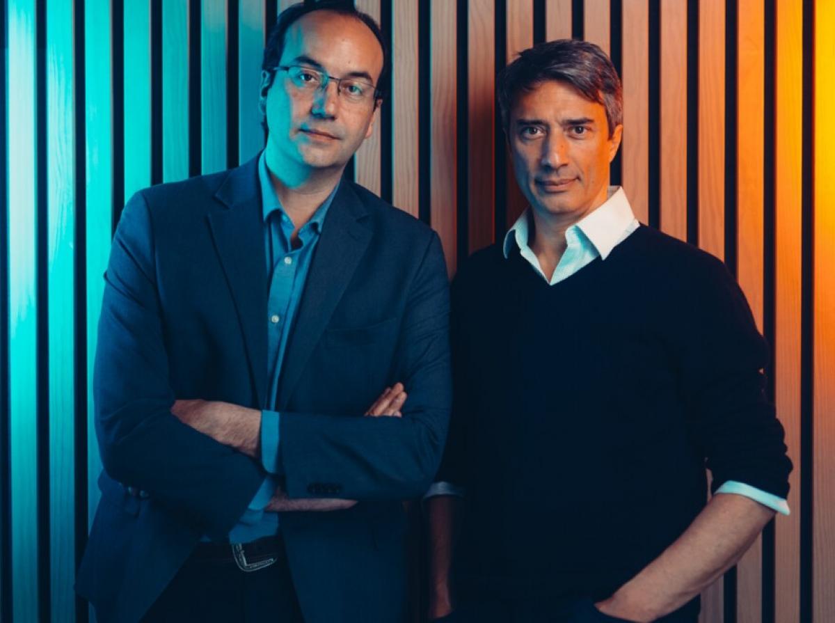 Two men posing in front of a colourful wall