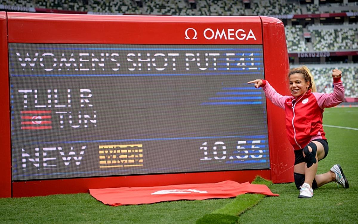 A woman pointing at a screen showing her world record mark in a stadium