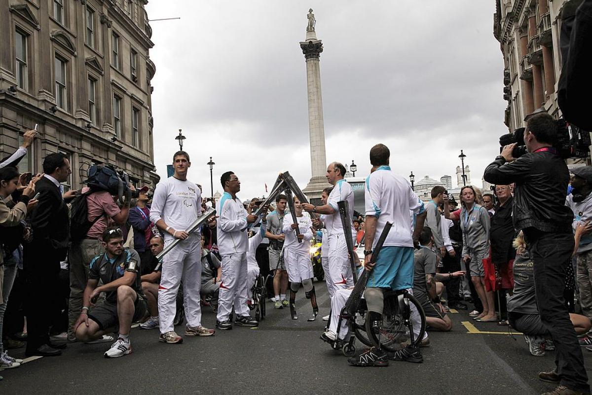 a group of Para athletes lighting a torch in front of Nelsons Column