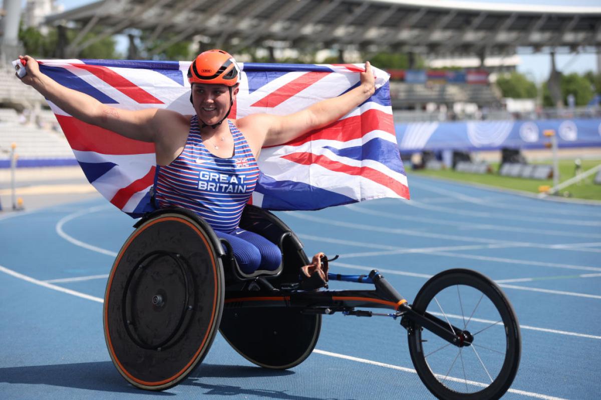 Wheelchair racer Eden Rainbow-Cooper holds up the Great Britain flag in celebration