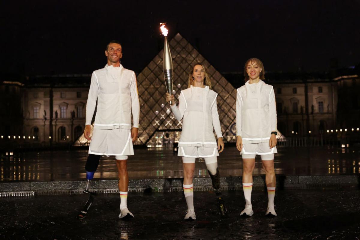 Marie-Amelie Le Fur holds the Olympic Torch in front of the Louvre