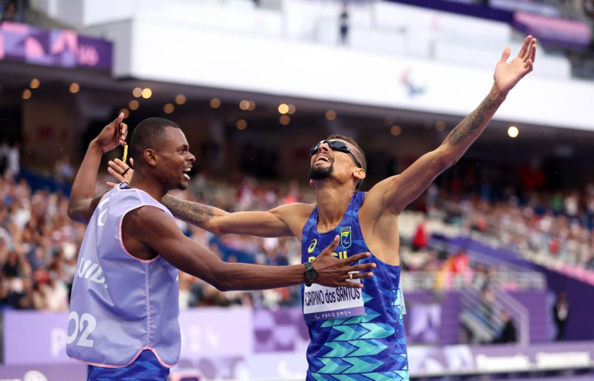 Agripinos dos Santos and his guide raise their arms in celebration