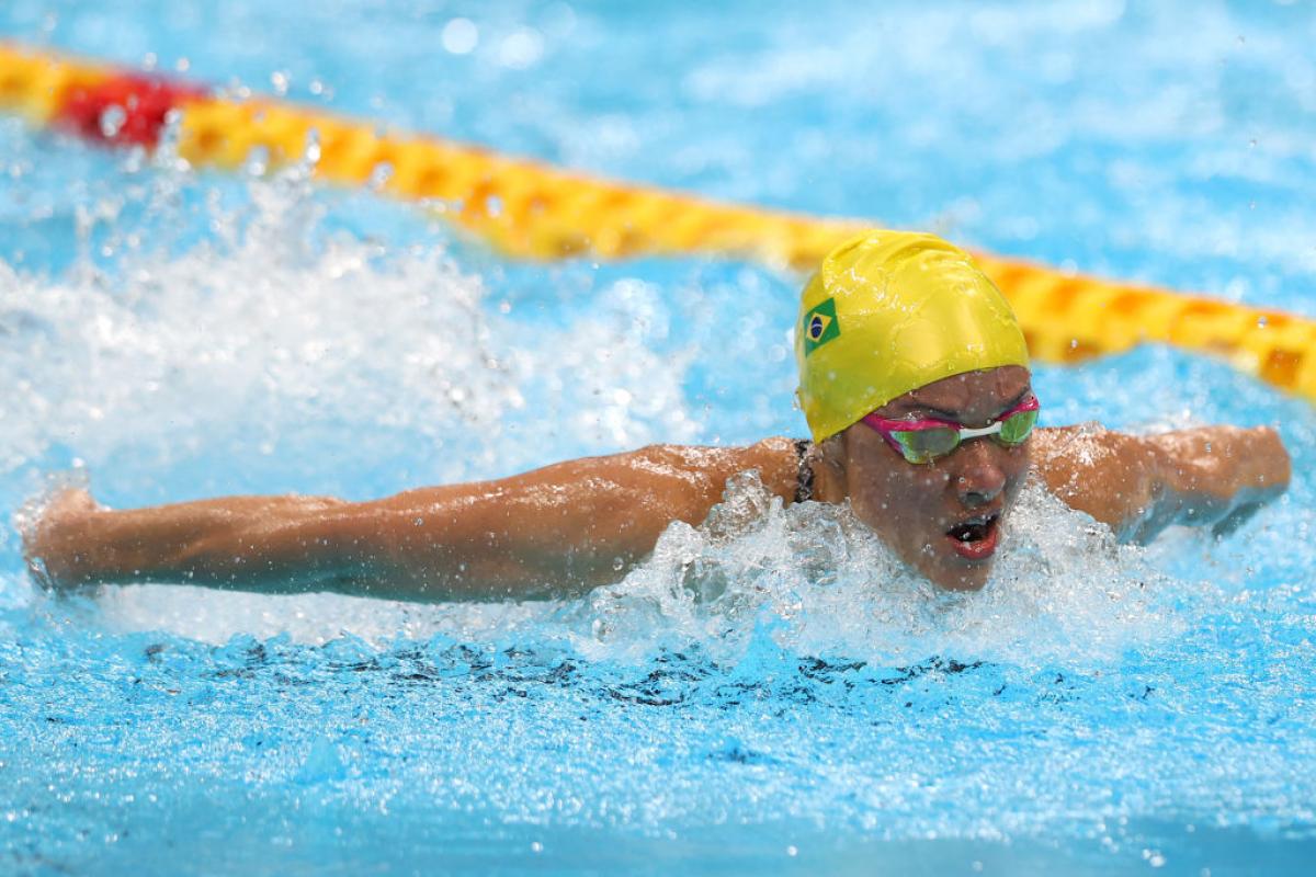 Brazilian swimmer Maria Carolina Santiago competes. She is wearing a yellow swimming cap and pink goggles