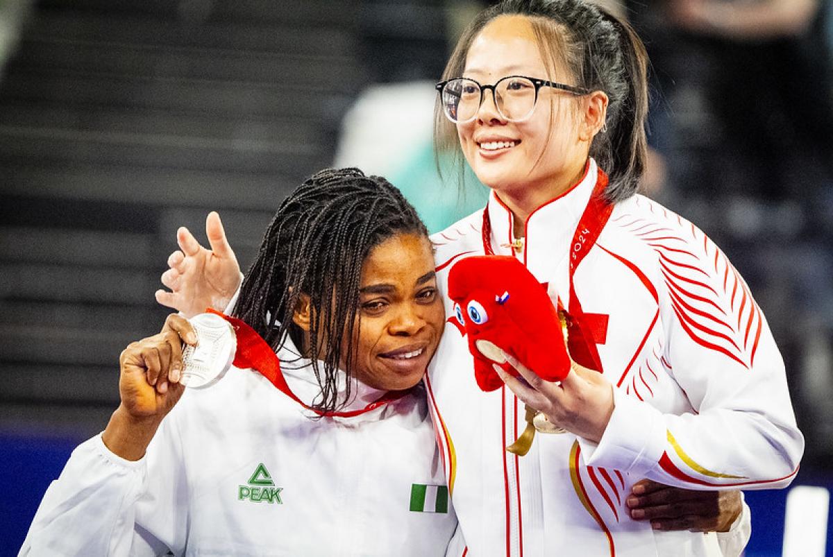 Two female athletes hugging with their medals