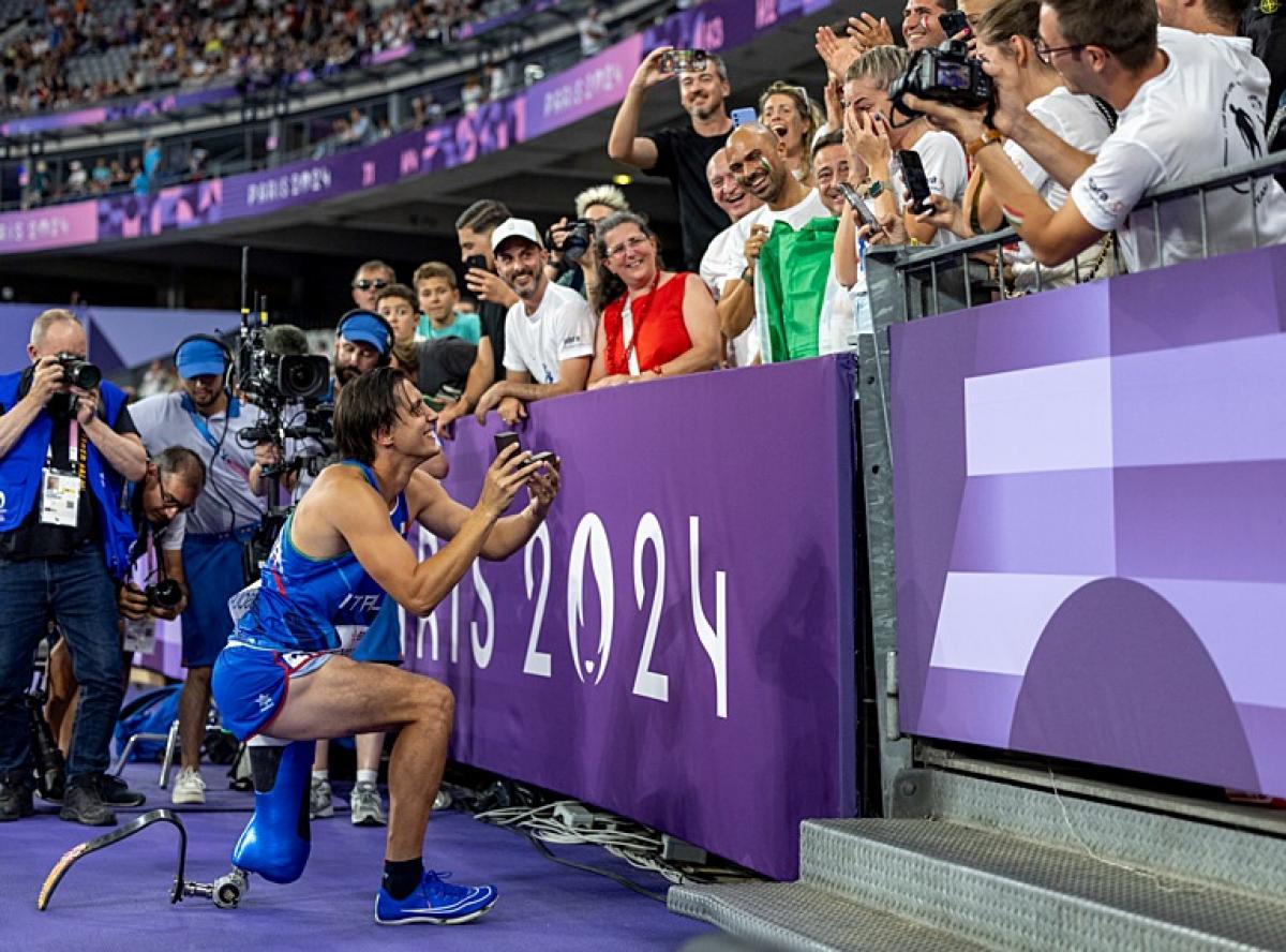 A man with a prosthetic leg kneeling to propose to his girlfriend in a packed stadium