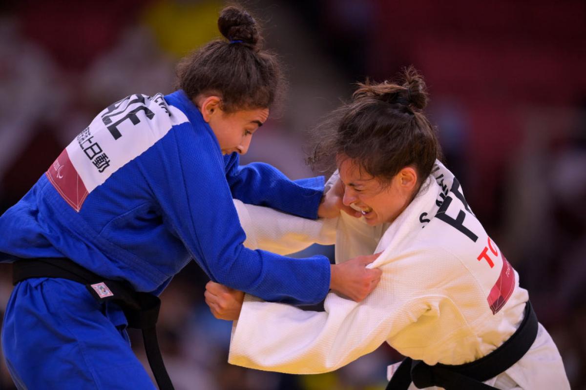 Two woman competing in Para judo grab each other by the arms