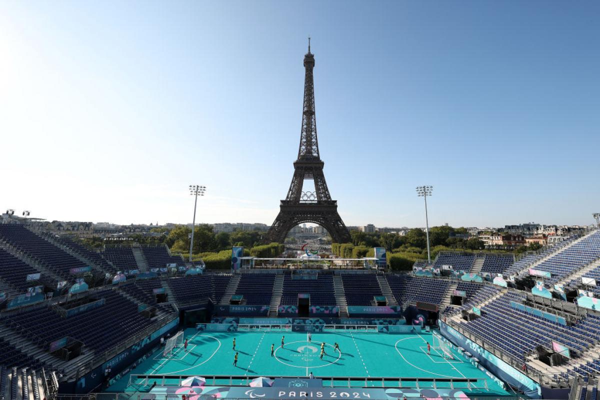 An outdoor blind football stadium, with the Eiffel Tower in the background