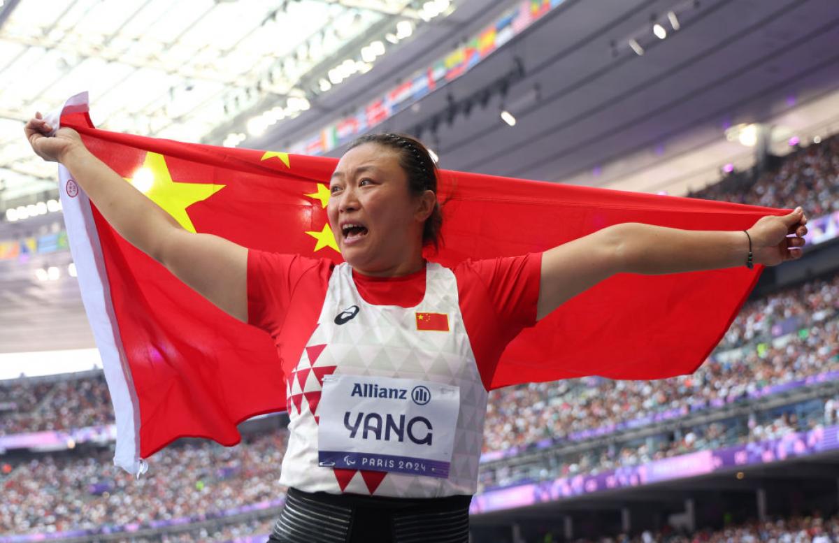A female athlete with the Chinese flag in a packed stadium