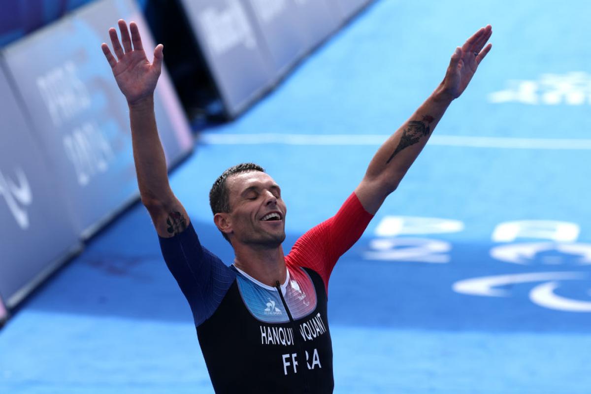 Para triathlete Alexis Hanquinquant raising his arms in celebration at the finish line