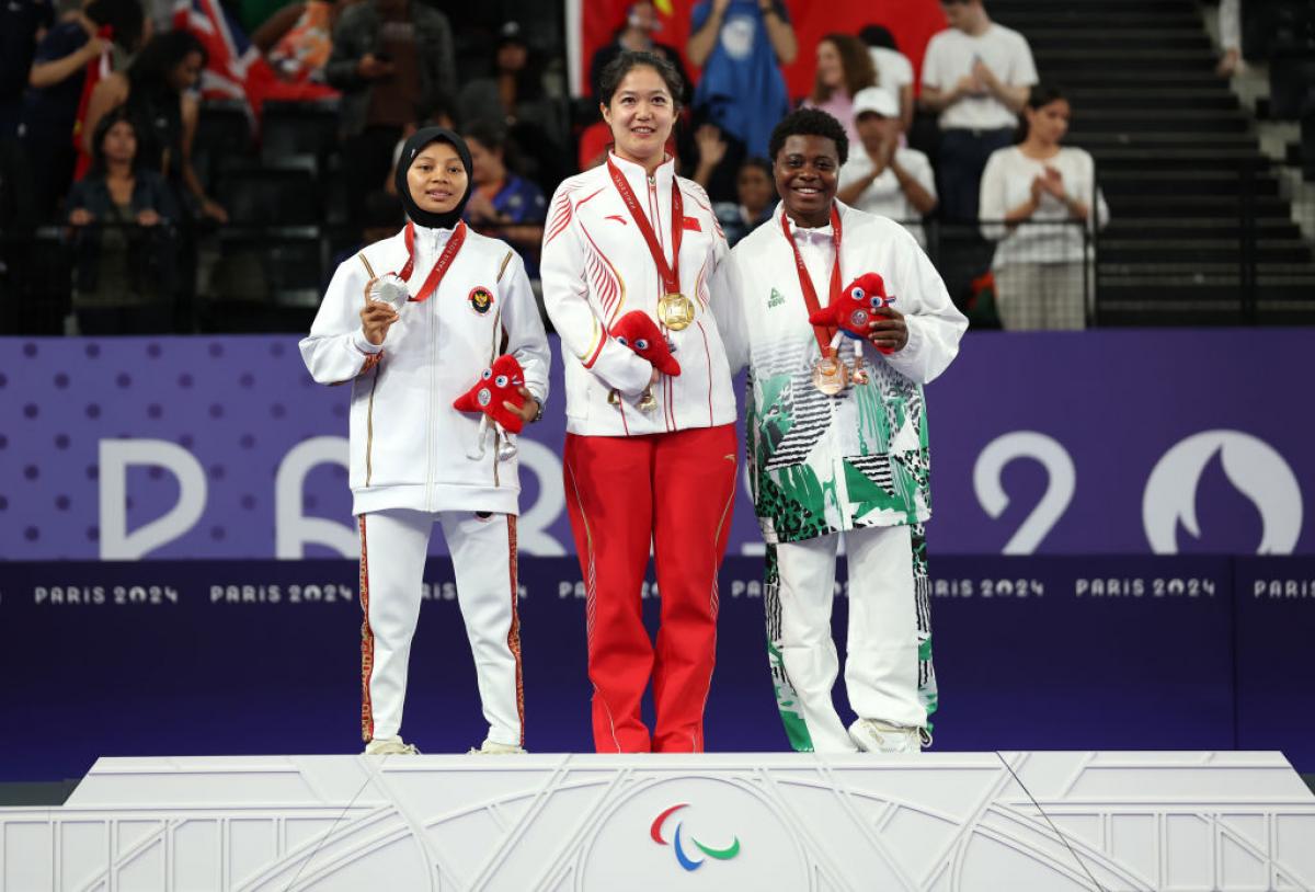 Three female Para badminton athletes with gold, silver and bronze medals on the podium