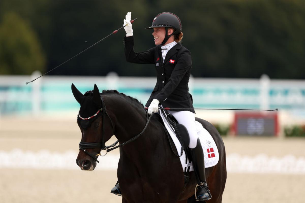 Para equestrian rider Katrine Kristensen smiles and waves on her horse