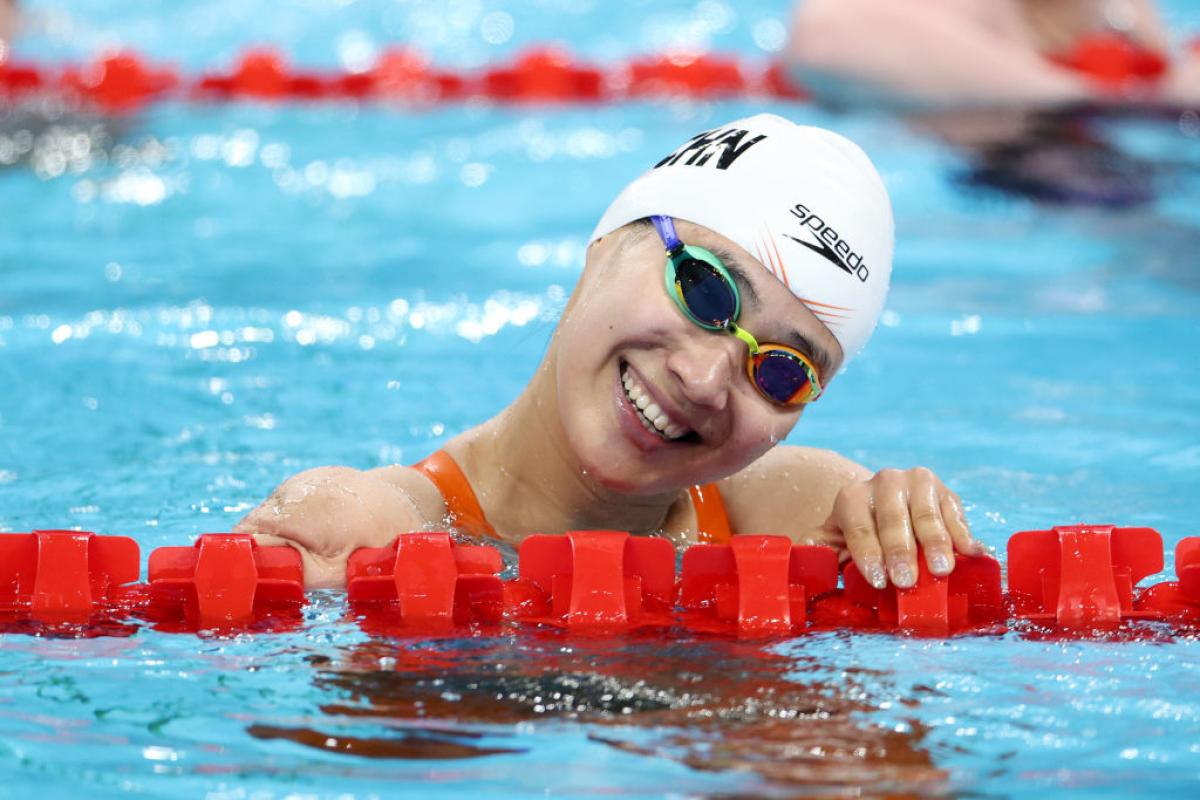 A female swimmer smiling from the pool
