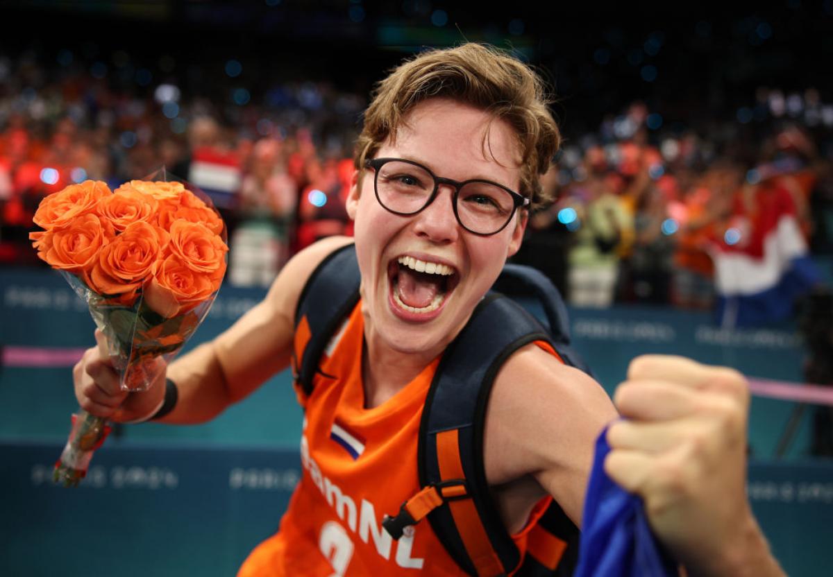 Bo Kramer celebrates into the camera while holding orange flowers