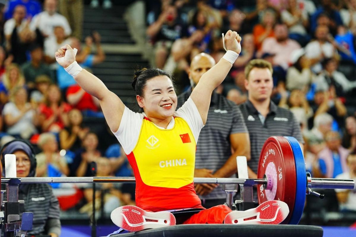 An athlete lifts her hands to celebrate after a successful lift