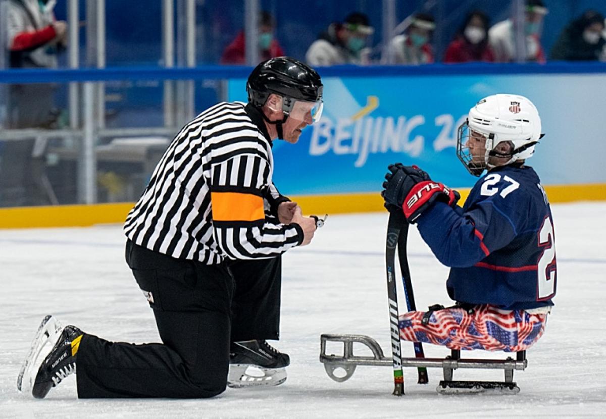 A Para ice hockey official and a player talking in an ice rink
