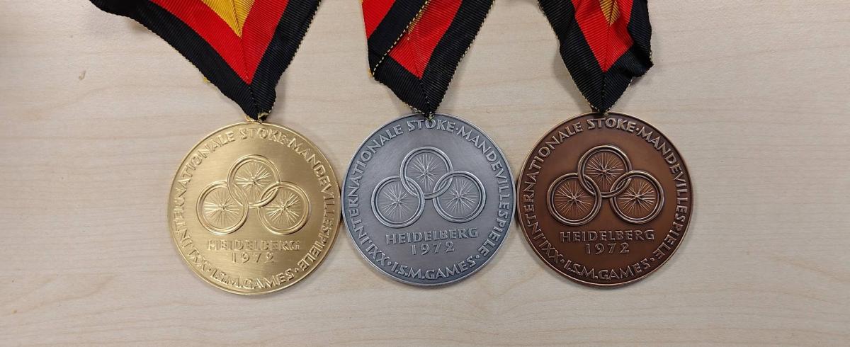 The front face of the Heidelberg 1972 Paralympic Games medals, shown in gold, silver and bronze.