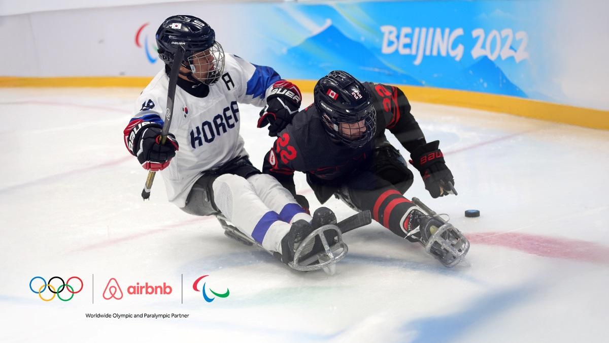 A banner with a photo of Para ice hockey players in action with the logo of Airbnb