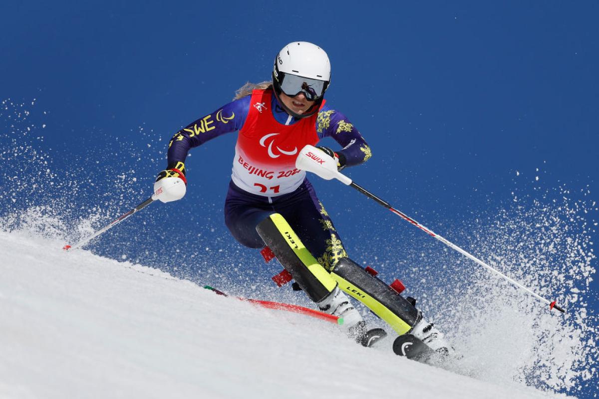 A female Para alpine skiing athlete in action.