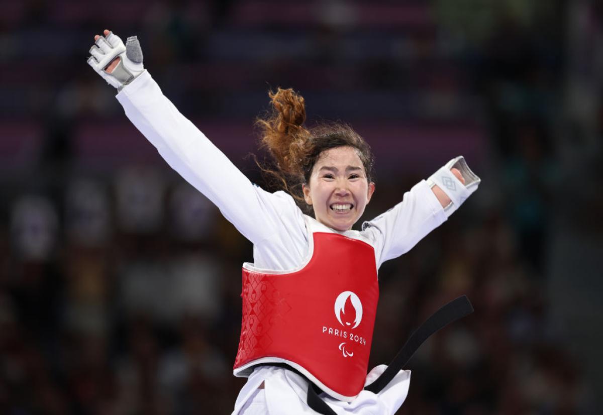 A female Para taekwondo athlete is celebrating.