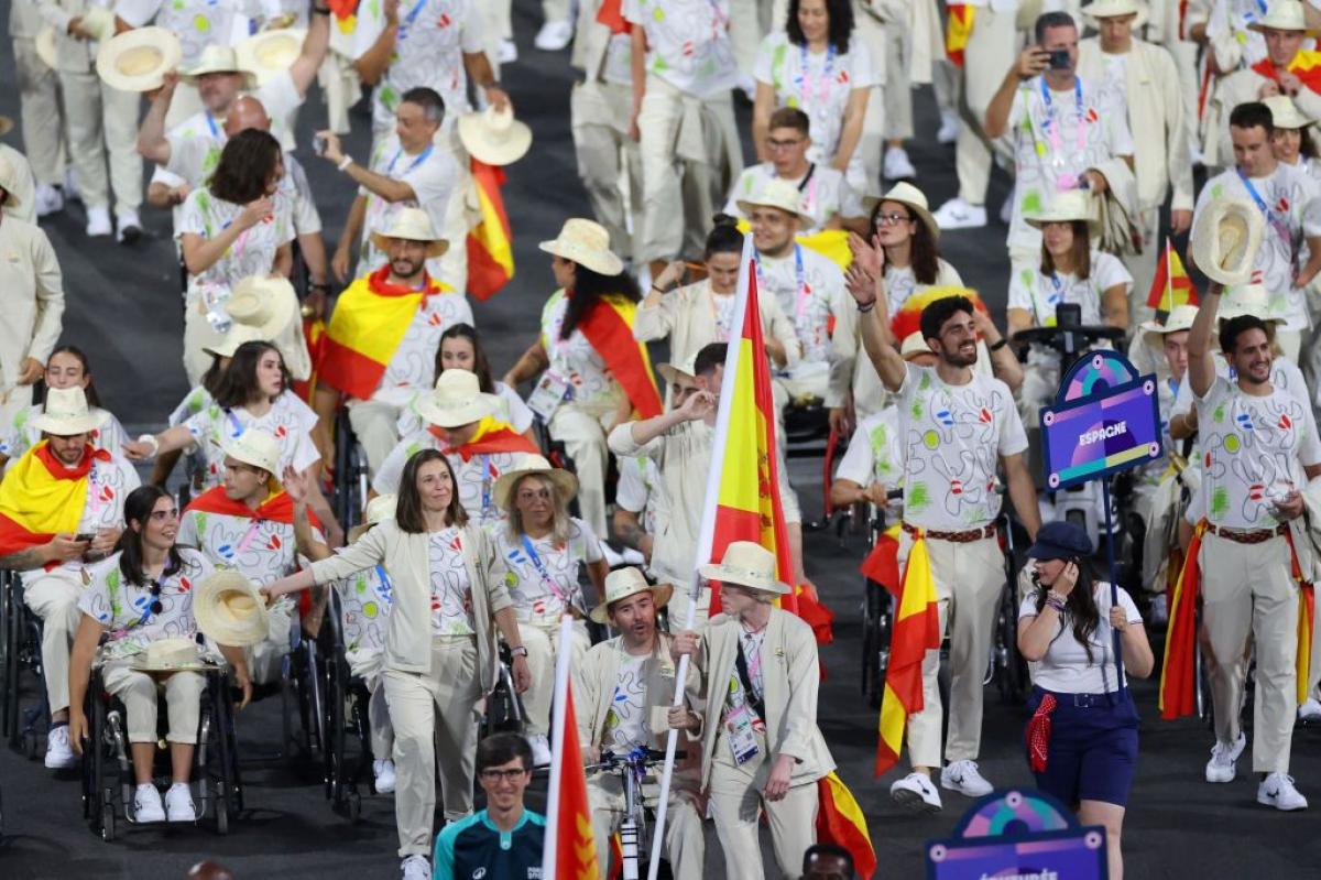 A large group of athletes taking part in the Parade of Nations at the Paris 2024 Opening Ceremony. They are holding the Spanish flag