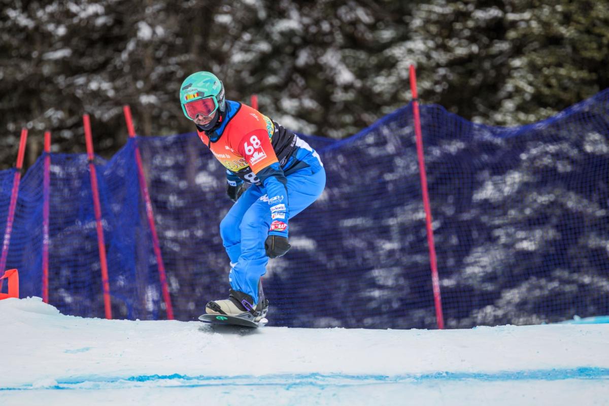 A male Para snowboard athlete is in competition.