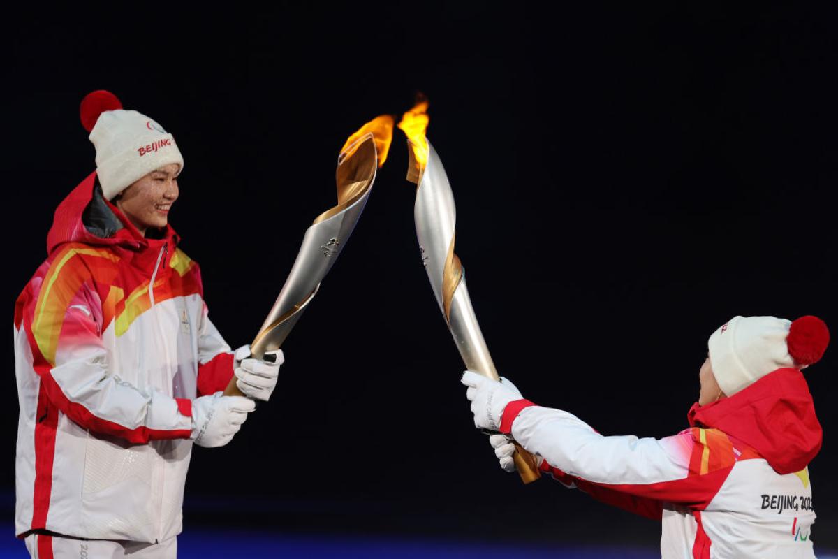 Two people carrying the Paralympic torch during the Opening Ceremony of the Beijing 2022 Paralympic Winter Games.
