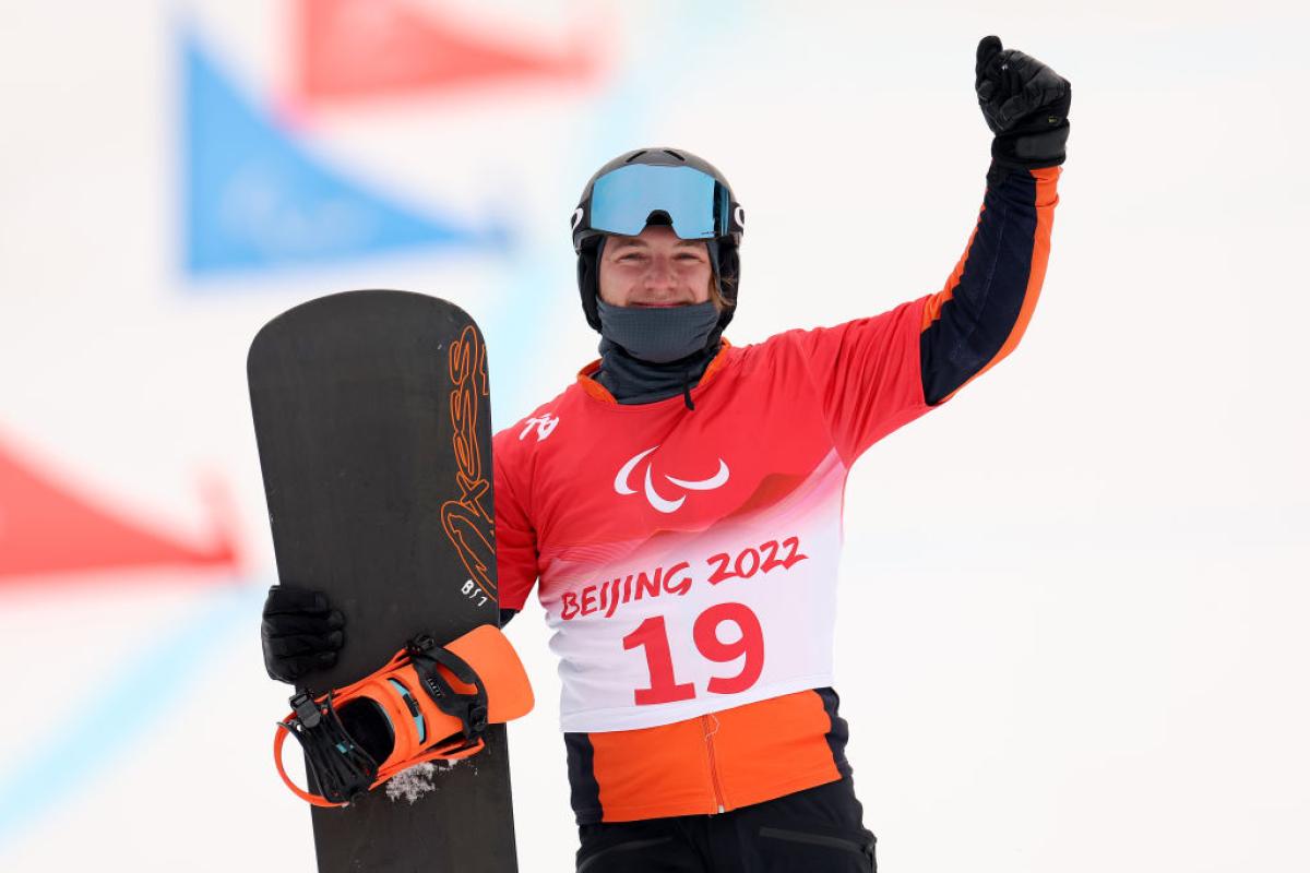 A male Para snowboard athlete posing for a photo while holding a snowboard