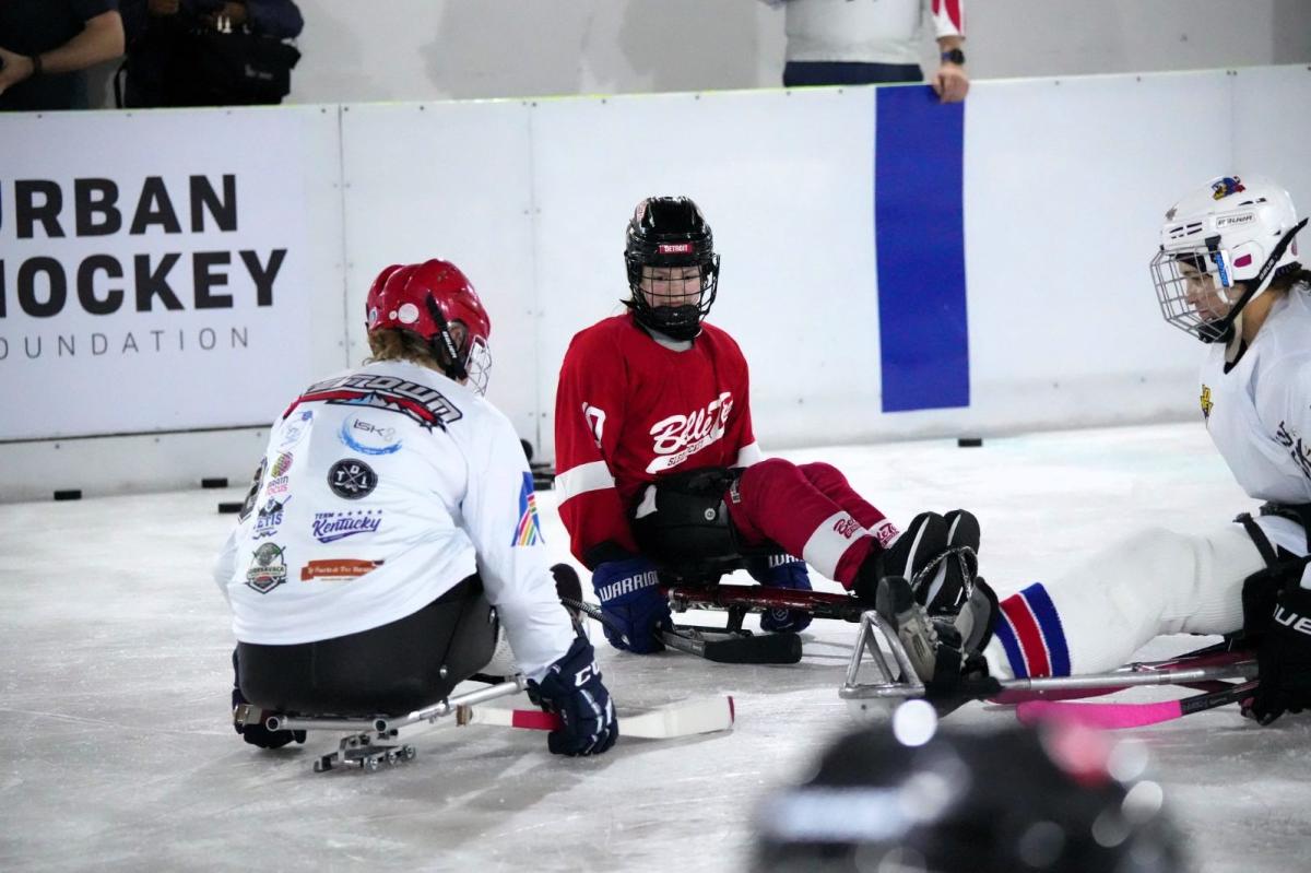 Three women on sledges in an ice rink