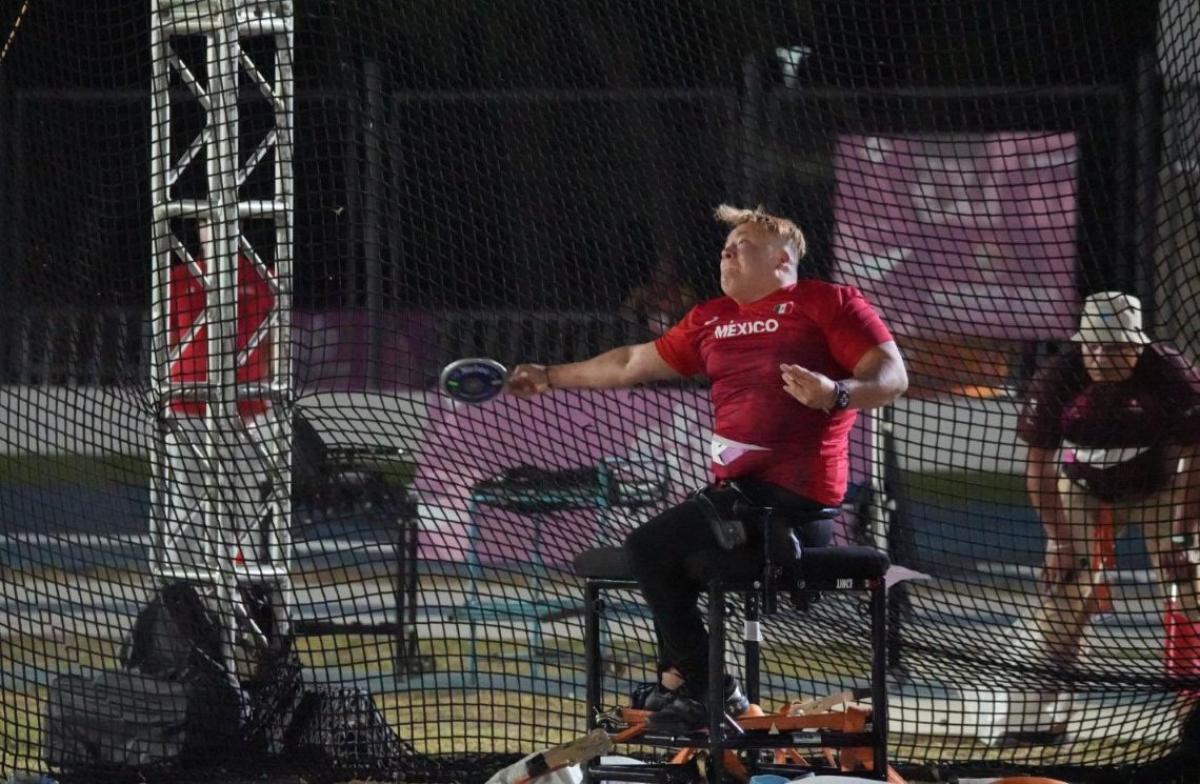 A female seated thrower competing observed by an official