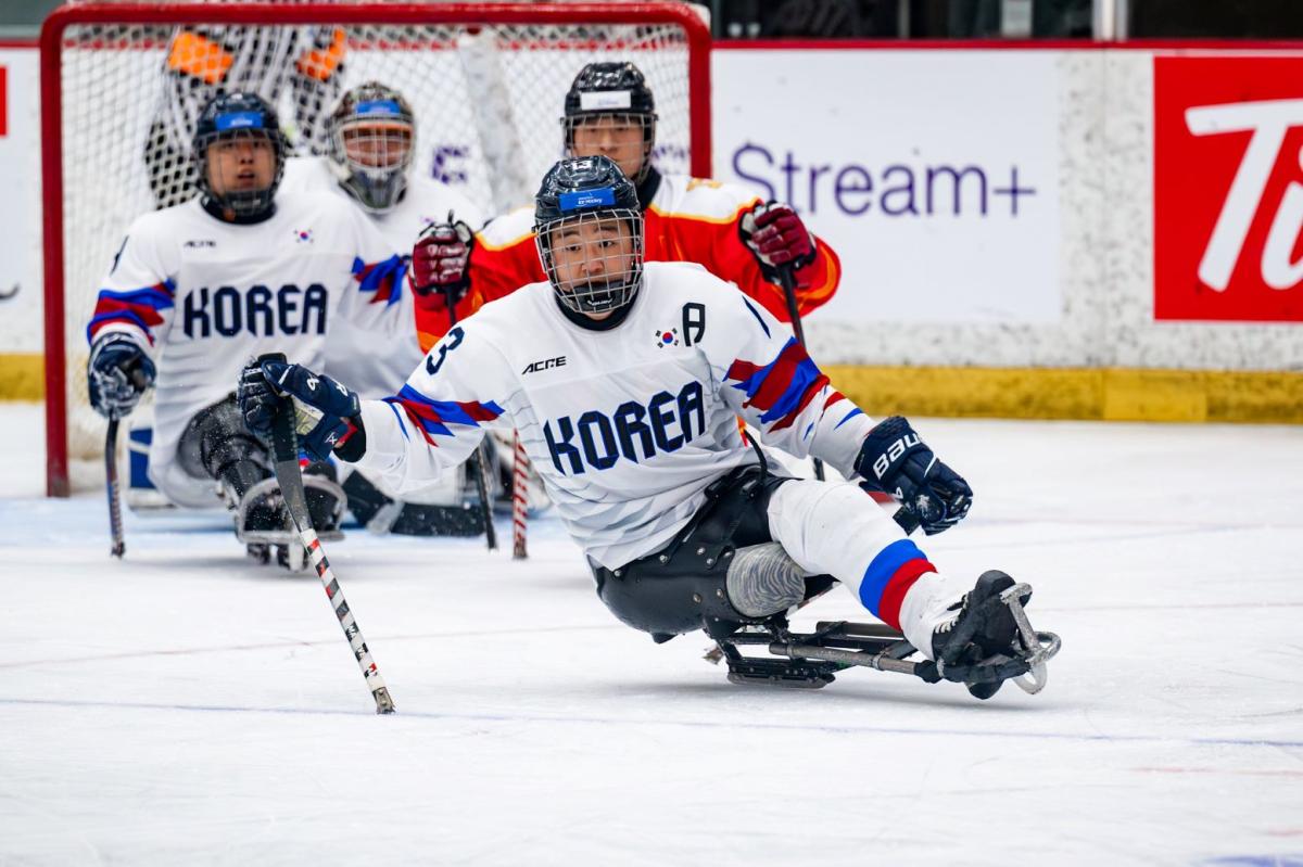 A Korean Para ice hockey player watched by three other players on ice