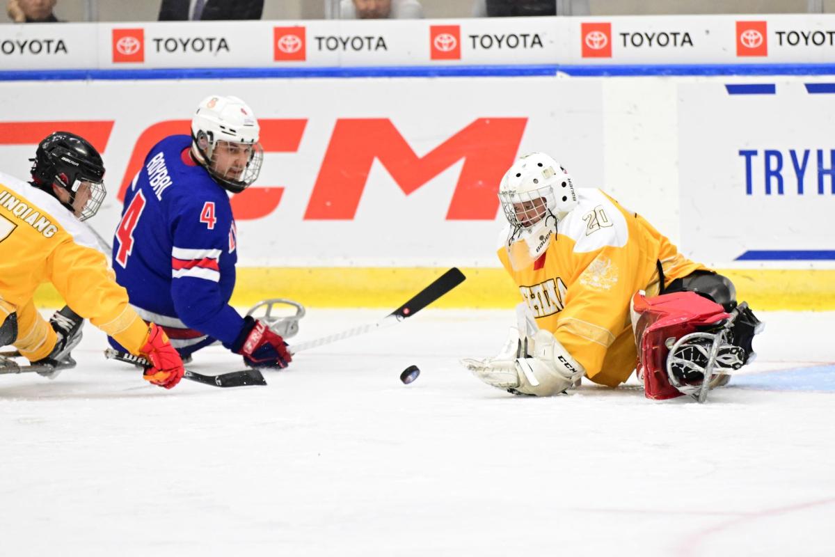 A Team USA Para ice hockey player against two Chinese players