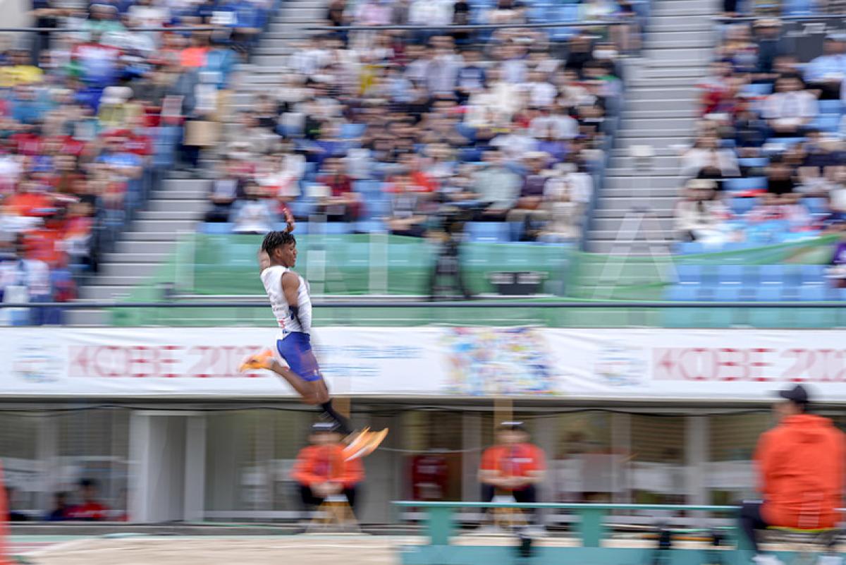 A man competing in the long jump in front of the crowd in a stadium