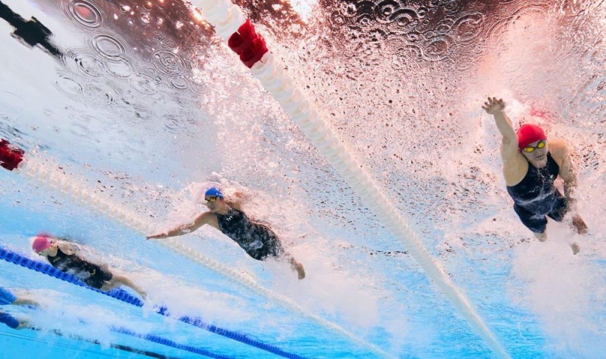 An underwater photo of three female Para swimmers