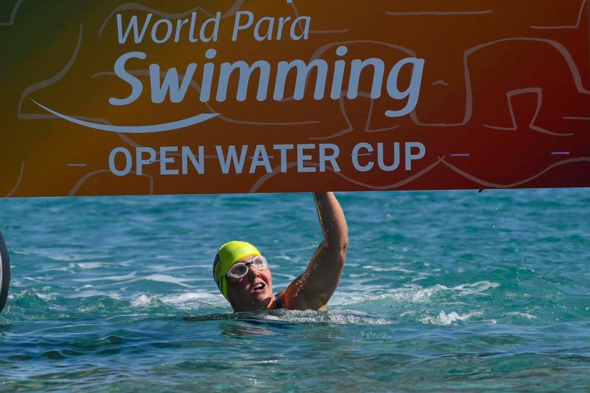 A female swimmer hitting the board at the finish line of the World Para Swimming Open Water Cup