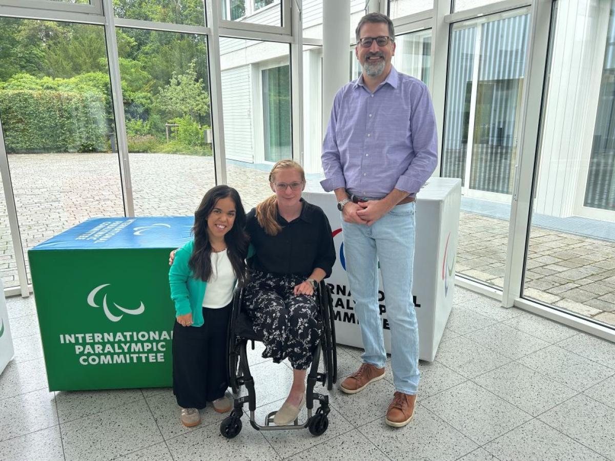 Two female Para athletes and IPC CEO Mike Peters pose for a photo at the IPC headquarters