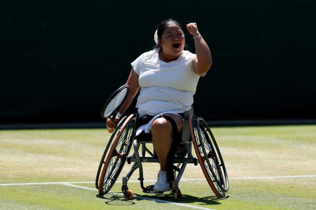 A female wheelchair tennis player is pumping her fist