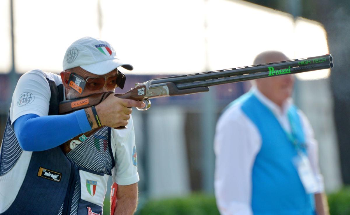 A male trap shooter observed by an official during competition
