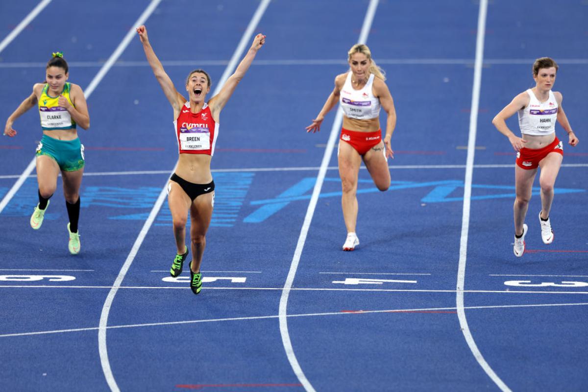 A woman crossing the line ahead of three other women in an athletics track
