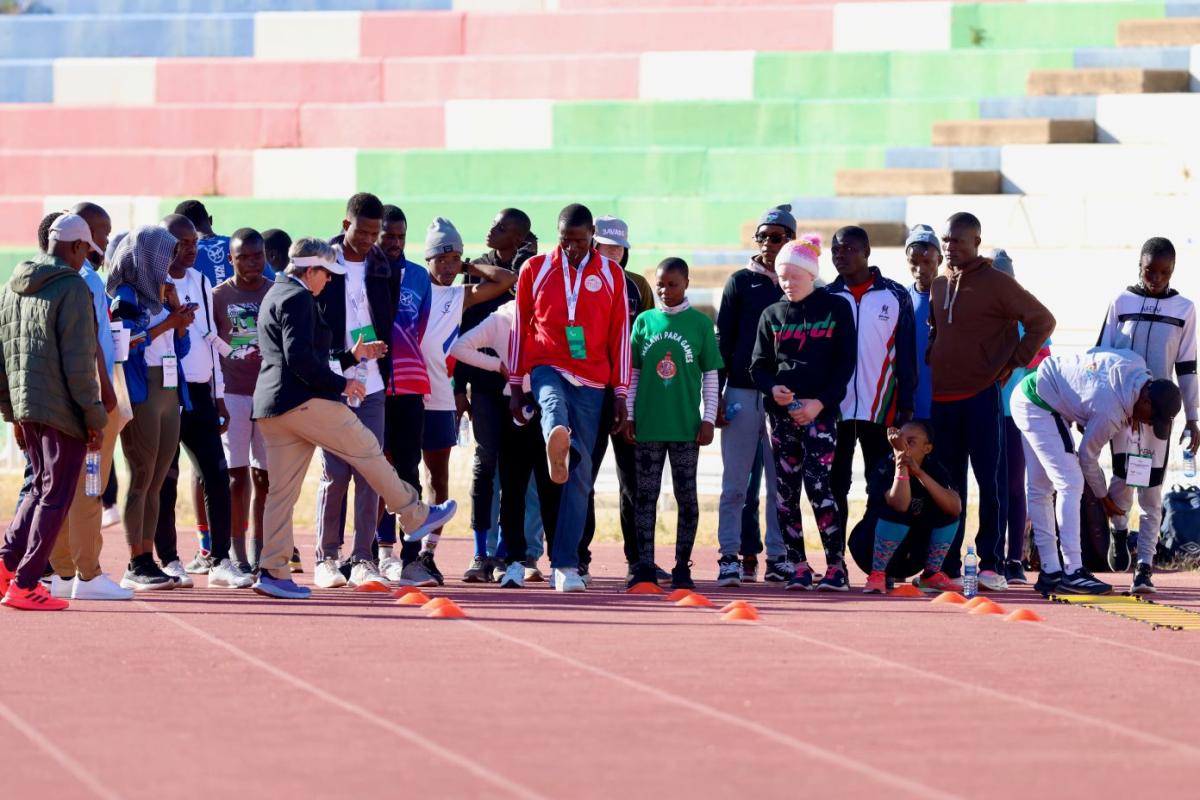 About 25 athletes gather on a track during a training camp