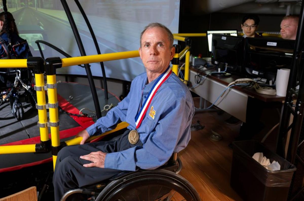 Rory Cooper sitting in a wheelchair with a medal around his neck