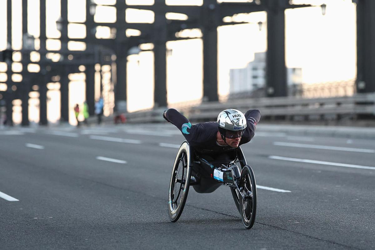 A male wheelchair racer crossing a bridge