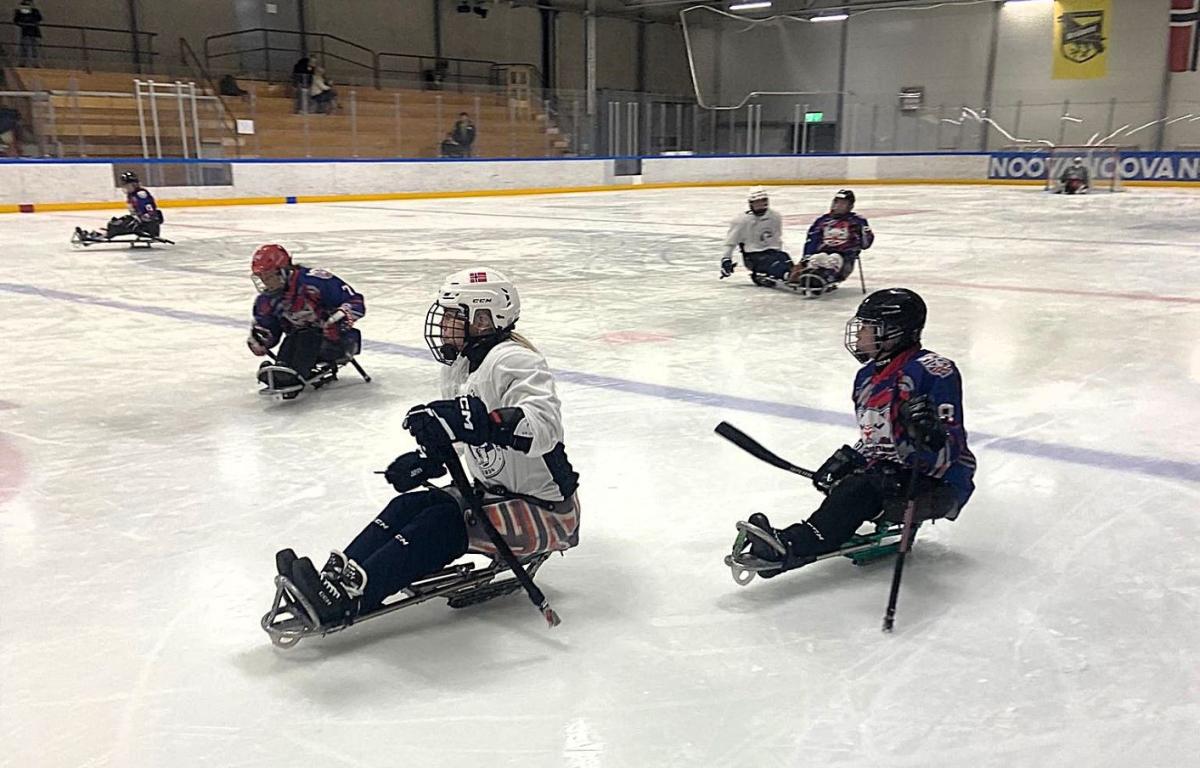 Six female Para ice hockey players in a game