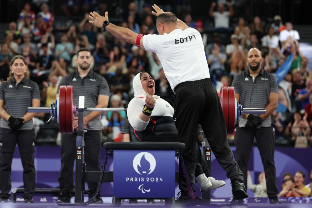 A female Egyptian Para powerlifter celebrates with her coach after her lift at Paris 2024