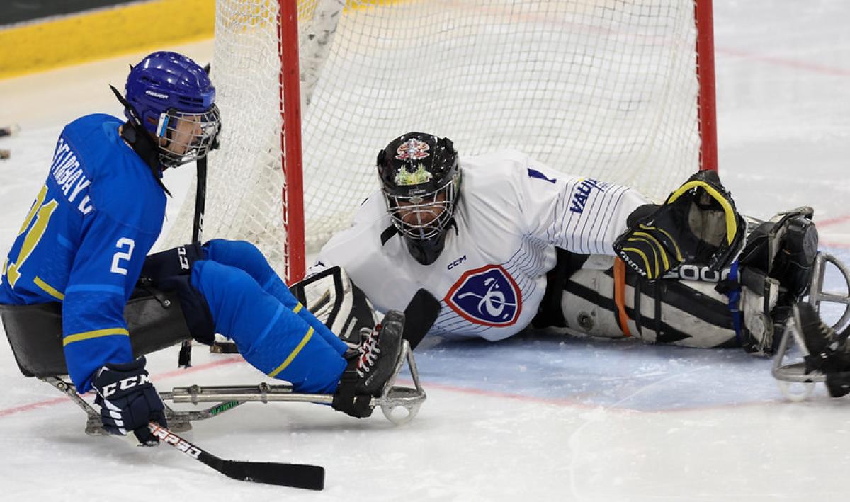A male Para ice hockey player taking a shot in front of the goaltender