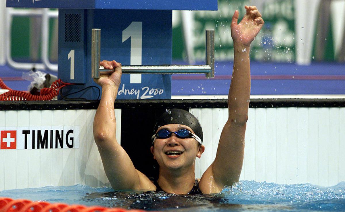 A female swimmer waving from the swimming pool at the Sydney 2000 Paralympic Games
