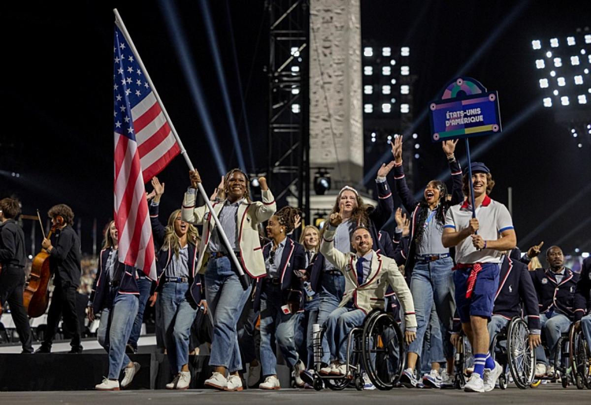 A group of athletes wearing a blue or white jacket are parading during the Opening Ceremony of Paris 2024