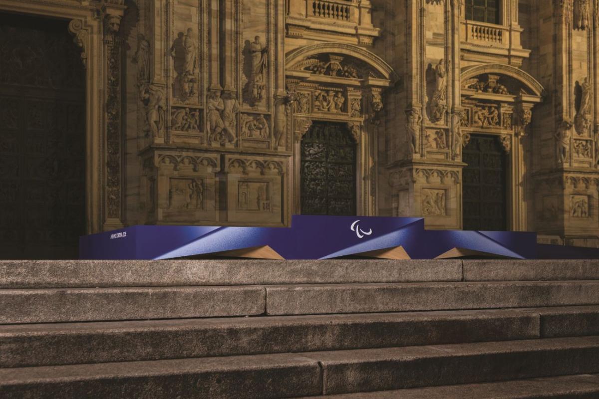 A purple podium with the Agitos logo in the centre is placed in front of a historic building