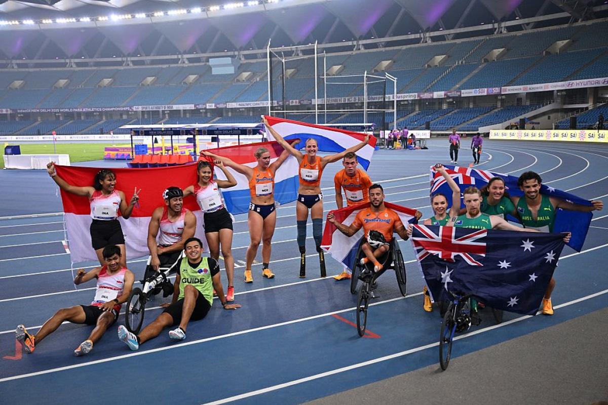 Athletes celebrate with their country flags on finish line 