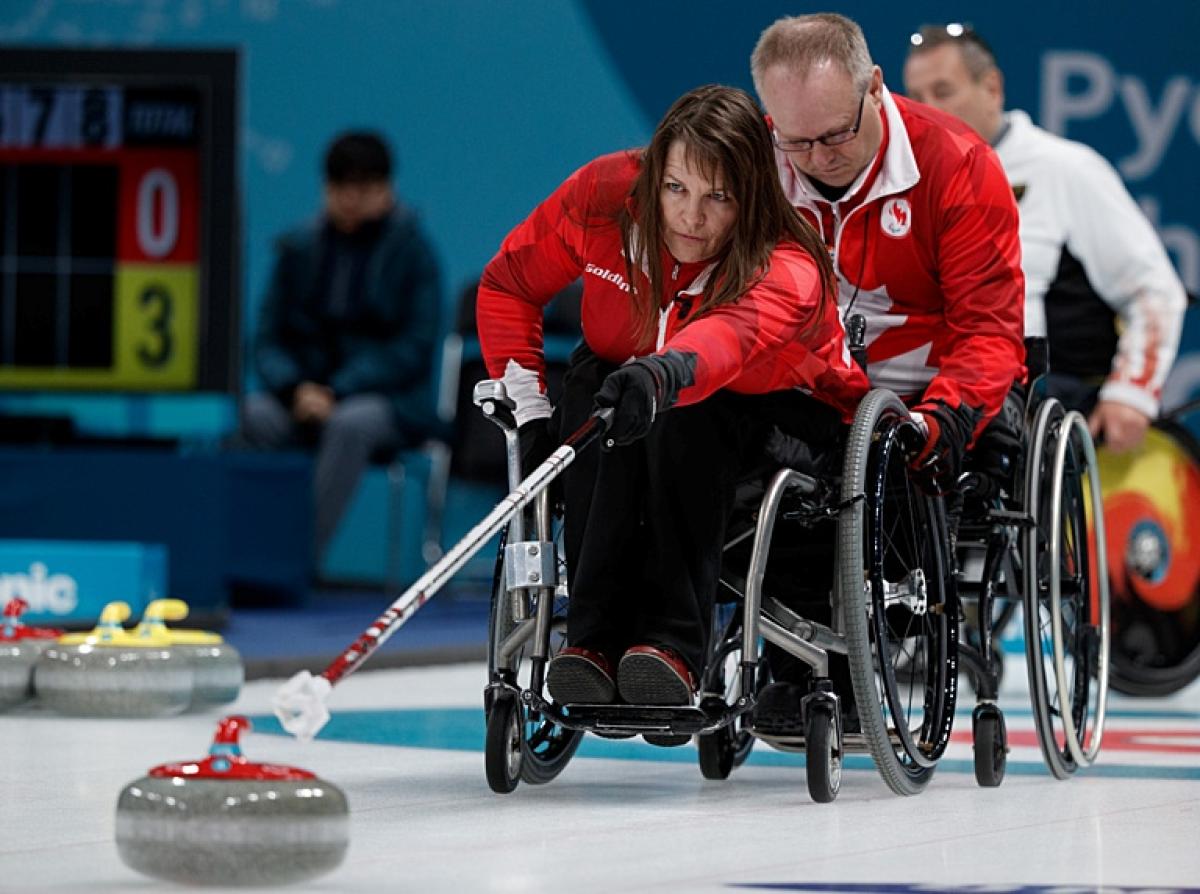 A female wheelchair curling athlete is in action at the PyeongChang 2018 Paralympic Winter Games