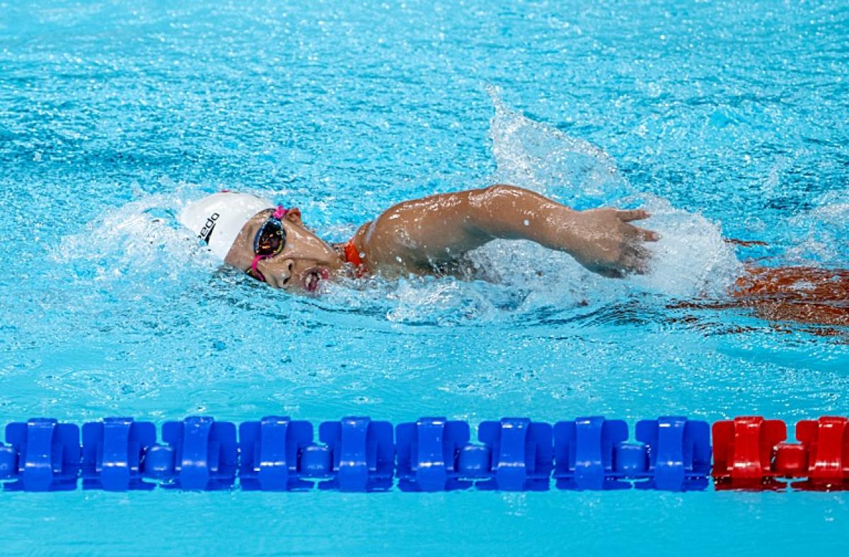 A female Para swimming athlete is competing in a freestyle event
